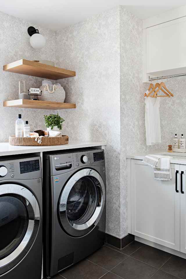 combined designer mudroom laundry room with wood shelves and wallpaper